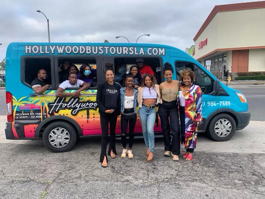 a group of tourists pose for a photo in front of the hollywood bus tours van