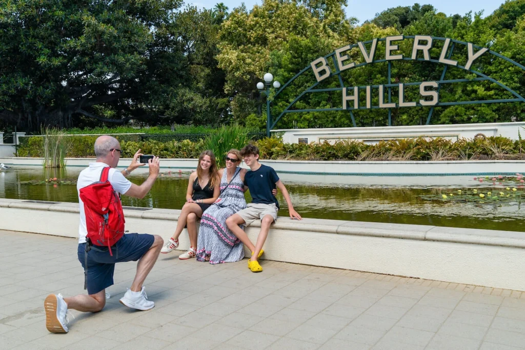 Tourists taking a photo in front of the Beverly Hills sign