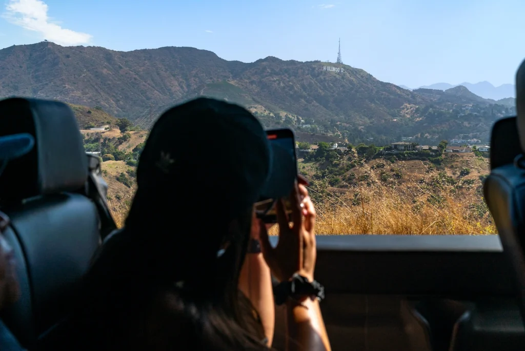 Tourist taking a photo of the hollywood sign from a Hollywood Bus Tour