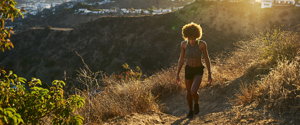 African woman hiking up a scenic trail at Runyon Canyon with city views in the background