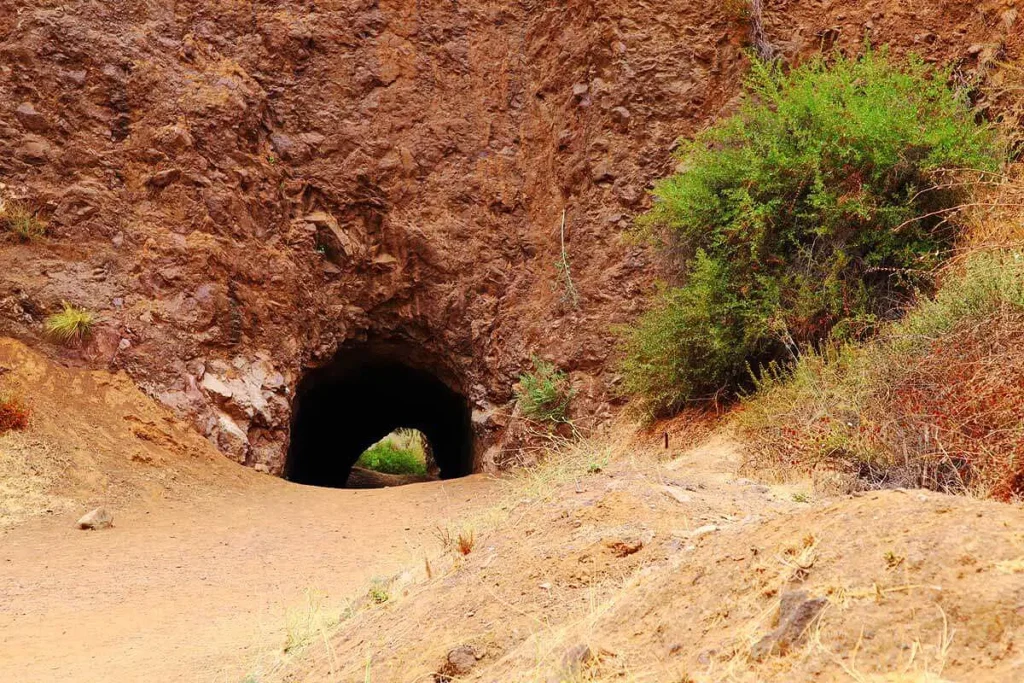 Rocky entrance of Bronson Canyon Cave surrounded by rugged hills and sparse vegetation
