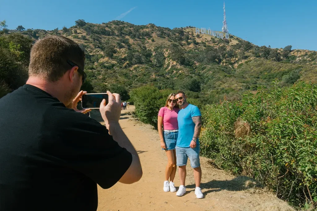 Smiling couple taking a picture together on the Hollywood Trail with city views in the background