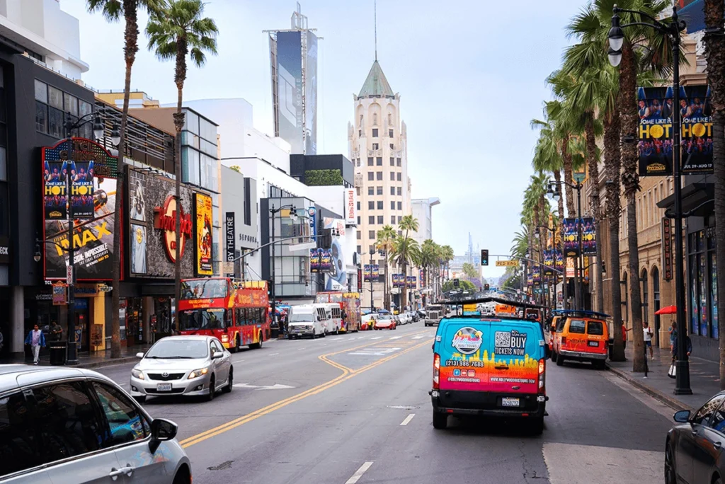 Hollywood tour bus driving along Hollywood Boulevard with Walk of Fame stars and historic landmarks in view.