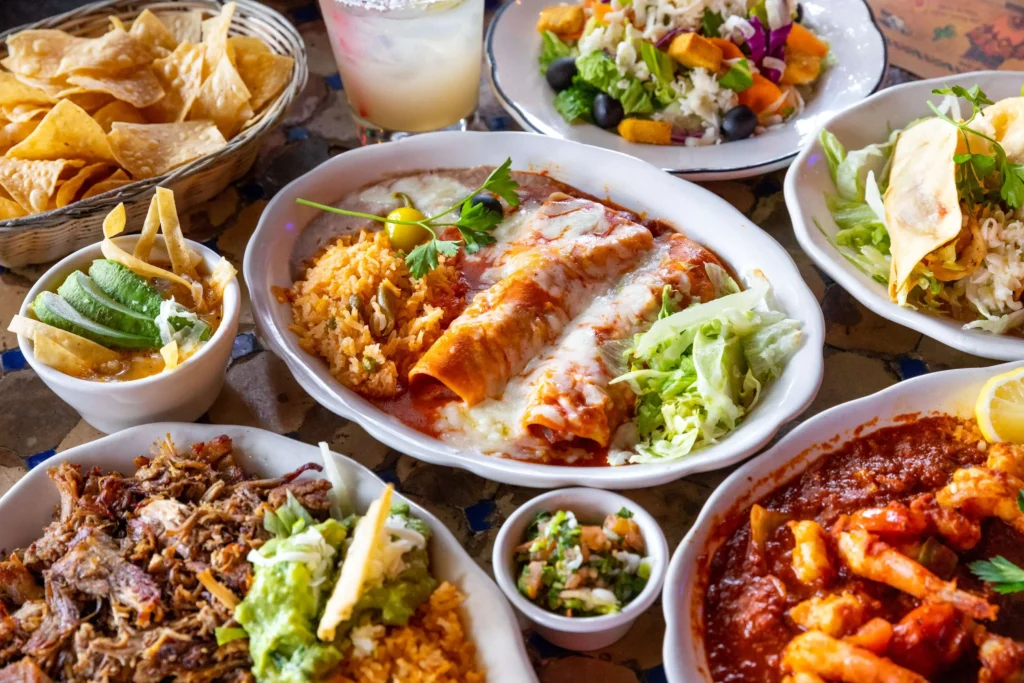 Close-up view of El Compadre restaurant dishes, showcasing colorful and flavorful Mexican cuisine including sizzling fajitas, rice, beans, and fresh garnishes.