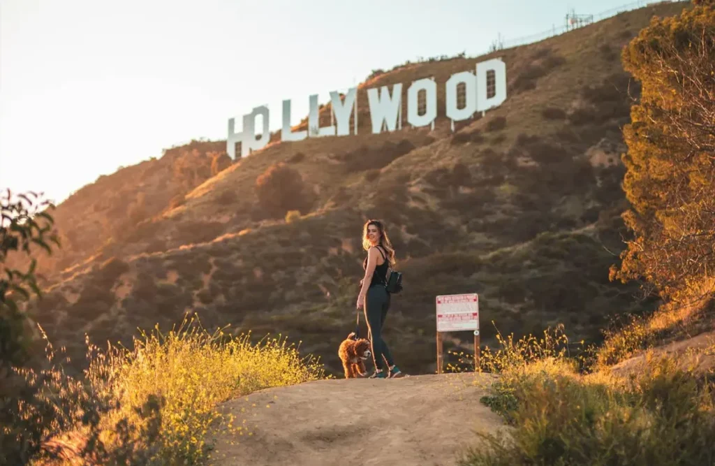 Woman hiking up a dirt trail in the Hollywood Hills with city views below
