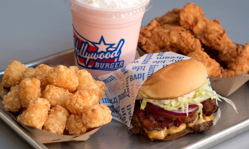 Close-up view of a meal from Hollywood Burger, featuring juicy burgers, crispy fries, and cold drinks arranged on a table, highlighting the fresh ingredients and vibrant presentation.
