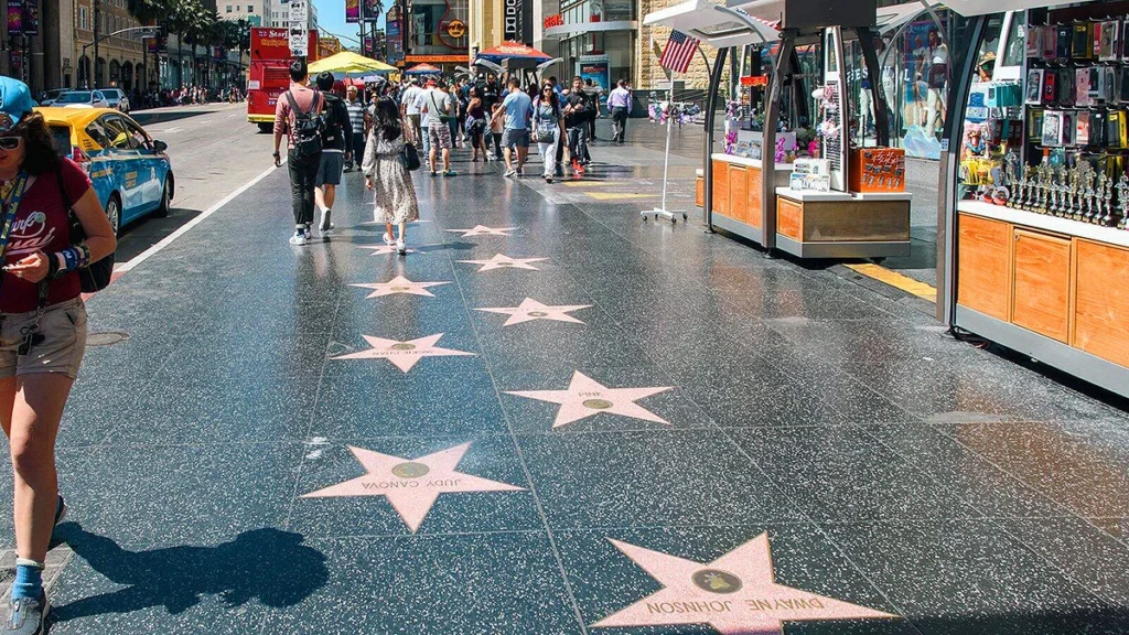 Close-up view of the Hollywood Walk of Fame sidewalk, featuring pink terrazzo and brass stars embedded in the pavement, honoring celebrities along Hollywood Boulevard.