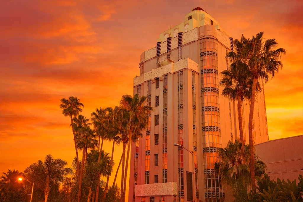 Historic Art Deco building in Los Angeles bathed in golden sunset light with palm trees, featured on Hollywood architecture bus tours