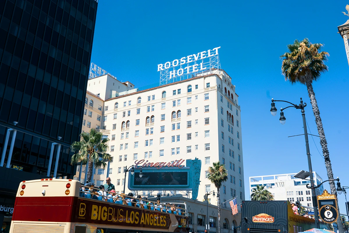 Historic Roosevelt Hotel on Hollywood Boulevard with classic white facade and rooftop sign, famous celebrity hangout on Hollywood bus tours