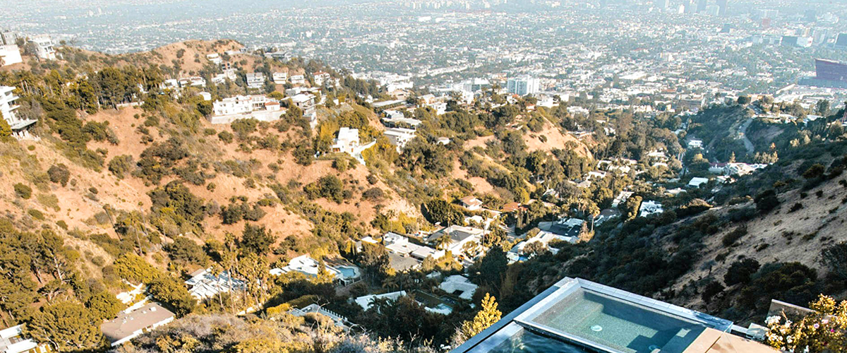 Panoramic view of Hollywood Hills and Los Angeles sprawl from scenic overlook with infinity pool, popular Hollywood bus tour photo stop