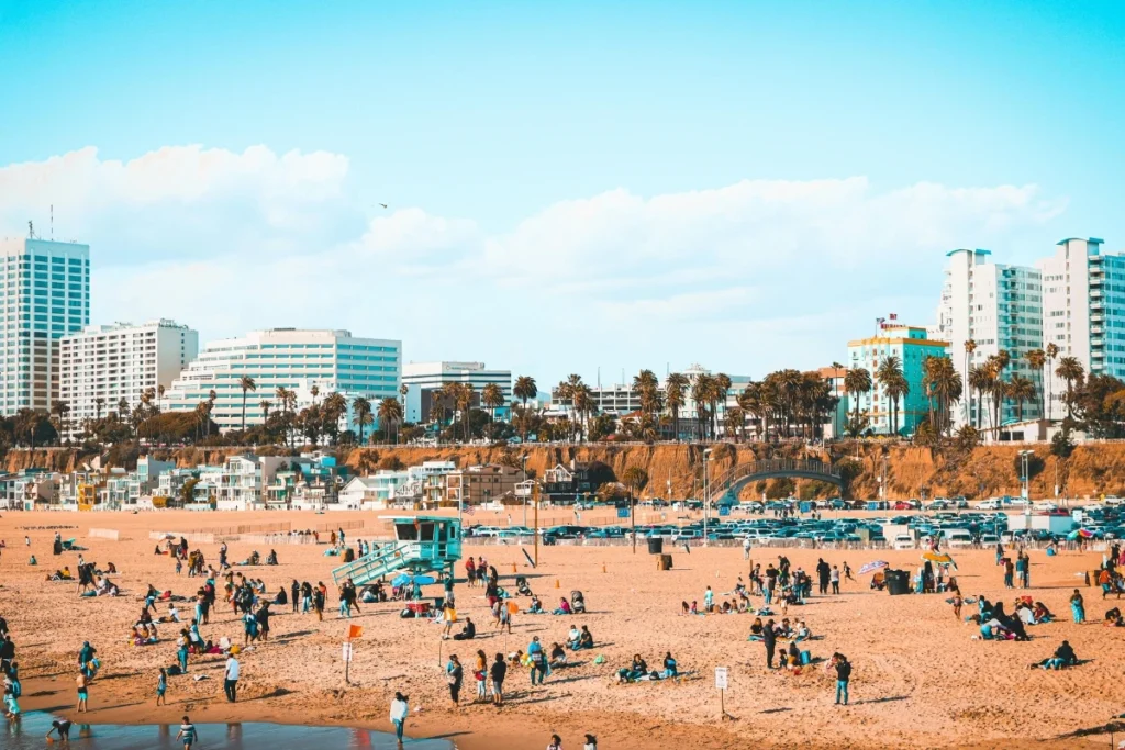 Aerial view of Santa Monica Beach with crowded sandy beach, lifeguard tower, and coastal city skyline backdrop