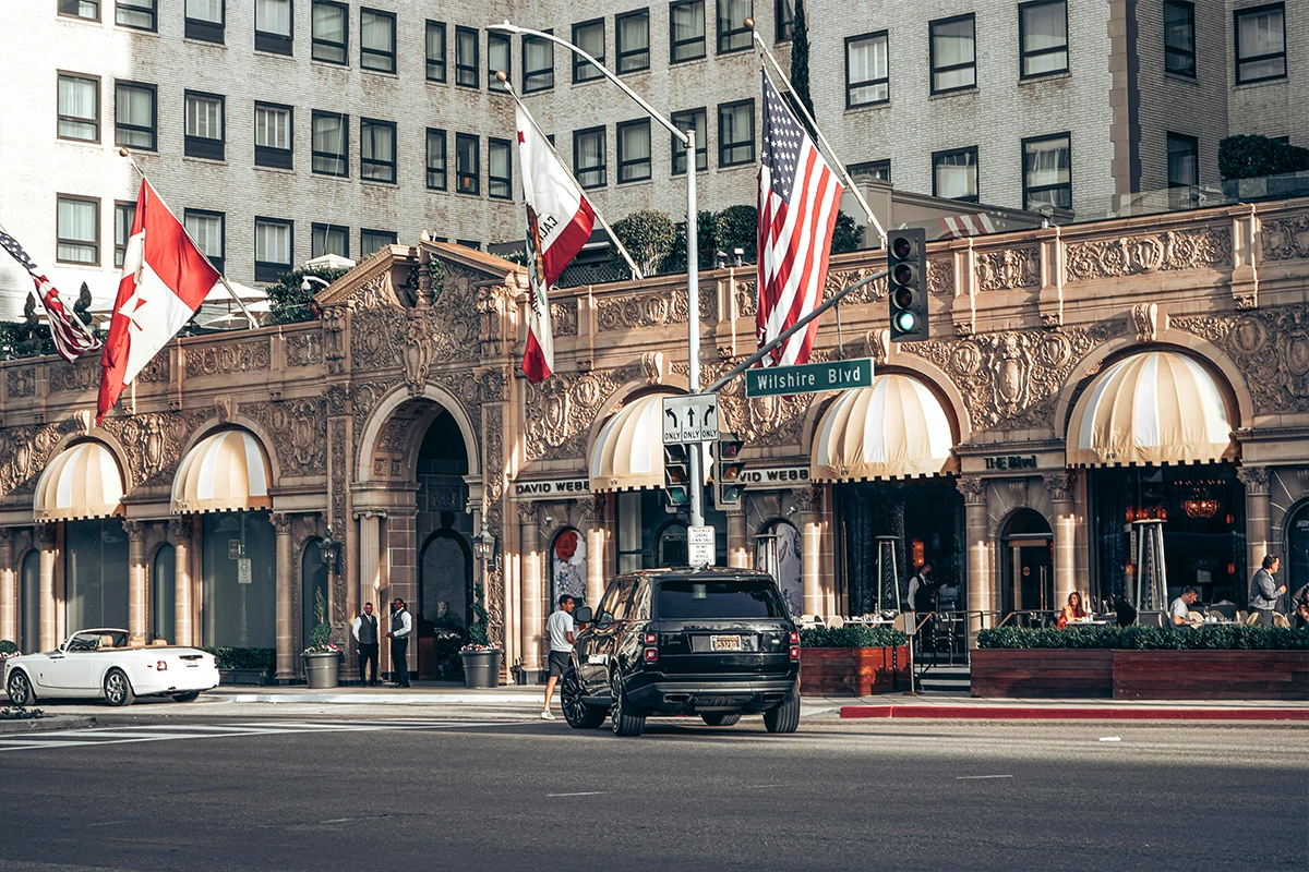 Historic ornate hotel building on Wilshire Boulevard with decorative architecture, American flag, and classic awnings