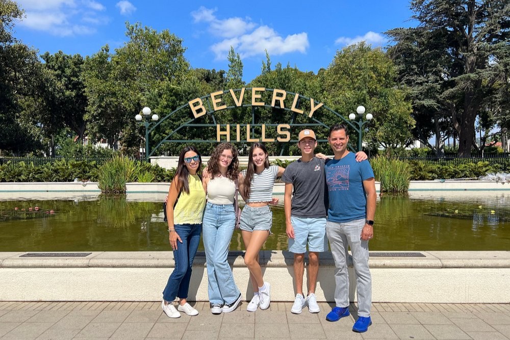 Happy family posing at famous Beverly Hills sign during daytime visit
