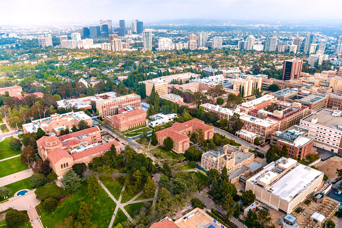 Aerial view of UCLA campus buildings with red tile roofs and city
