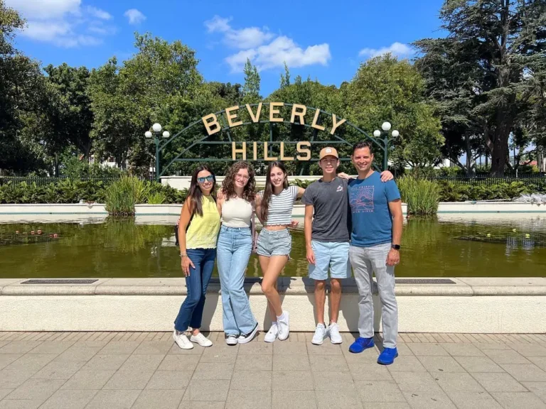 group of friends taking a photo beside the iconic Beverly Hills sign