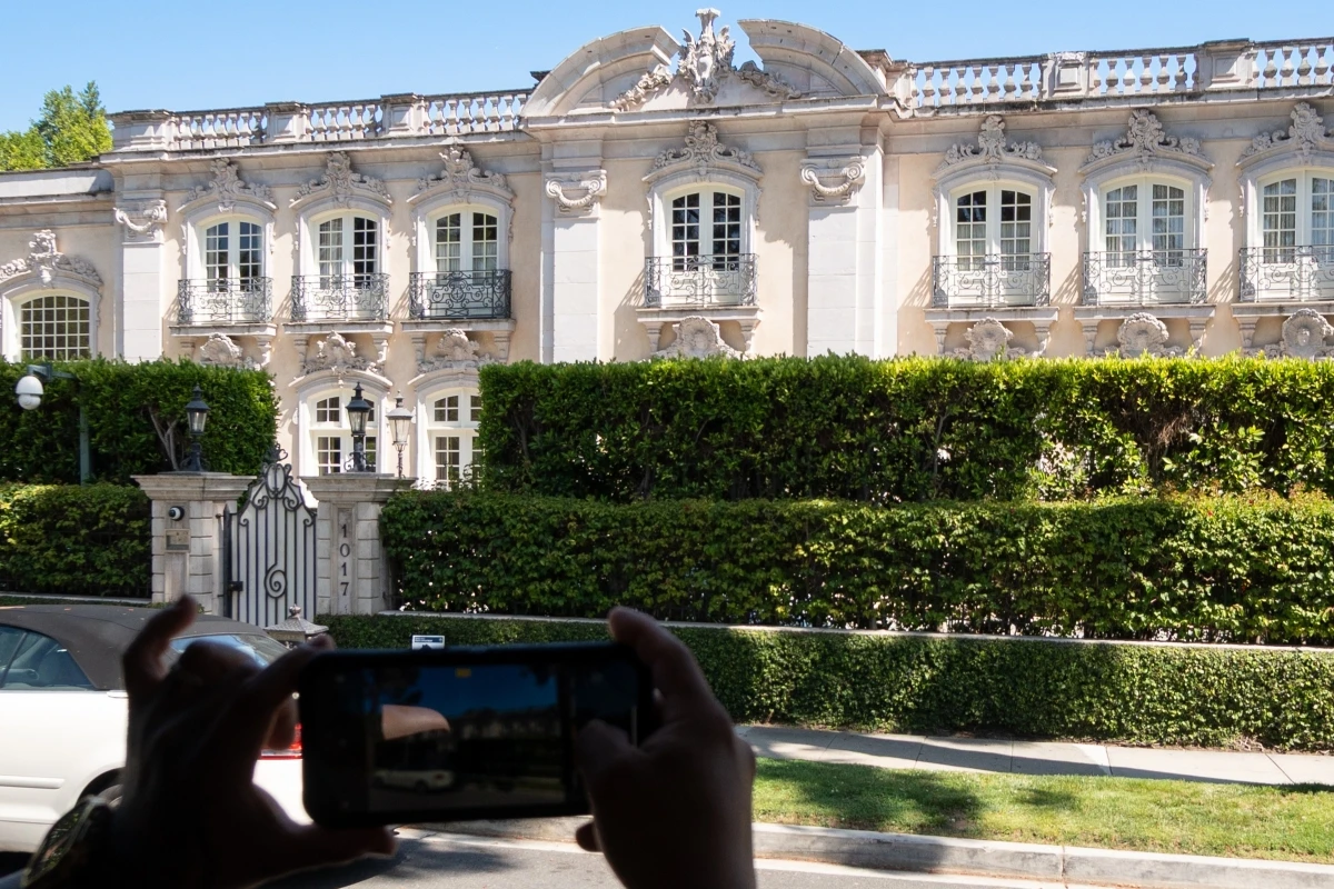 Ornate French Baroque-style mansion with white limestone facade, decorative moldings, and wrought iron balconies in Beverly Hills or Bel Air, visible during Hollywood celebrity homes bus tour experience.
