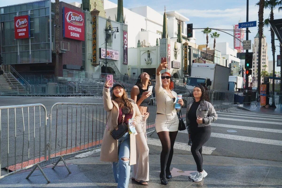 Group of visitors taking selfies on Hollywood Boulevard near the Walk of Fame and TCL Chinese Theatre