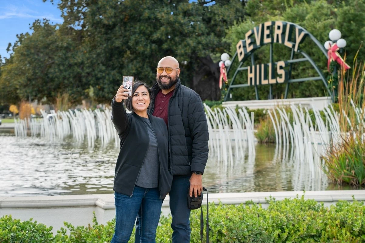Tourists taking selfie at iconic Beverly Hills sign fountain landmark