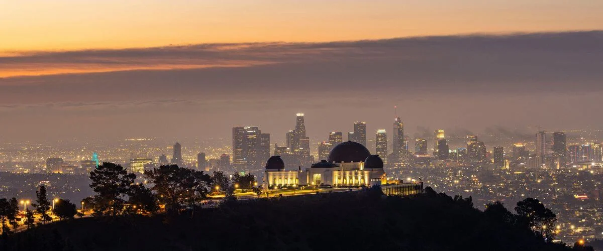 Griffith Observatory overlooking the downtown Los Angeles skyline at sunset with city lights glowing below