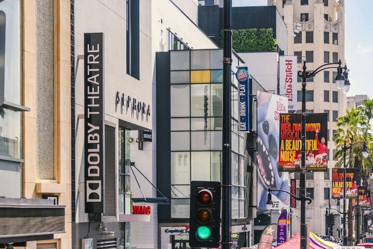 Street view of the Dolby Theatre on Hollywood Boulevard with theater signage, traffic lights, and nearby buildings