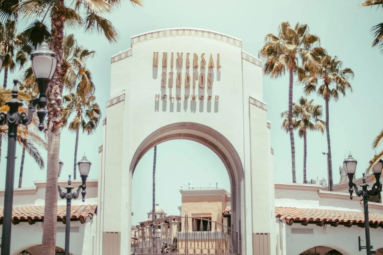 Iconic Universal Studios Hollywood entrance arch framed by palm trees on a sunny day