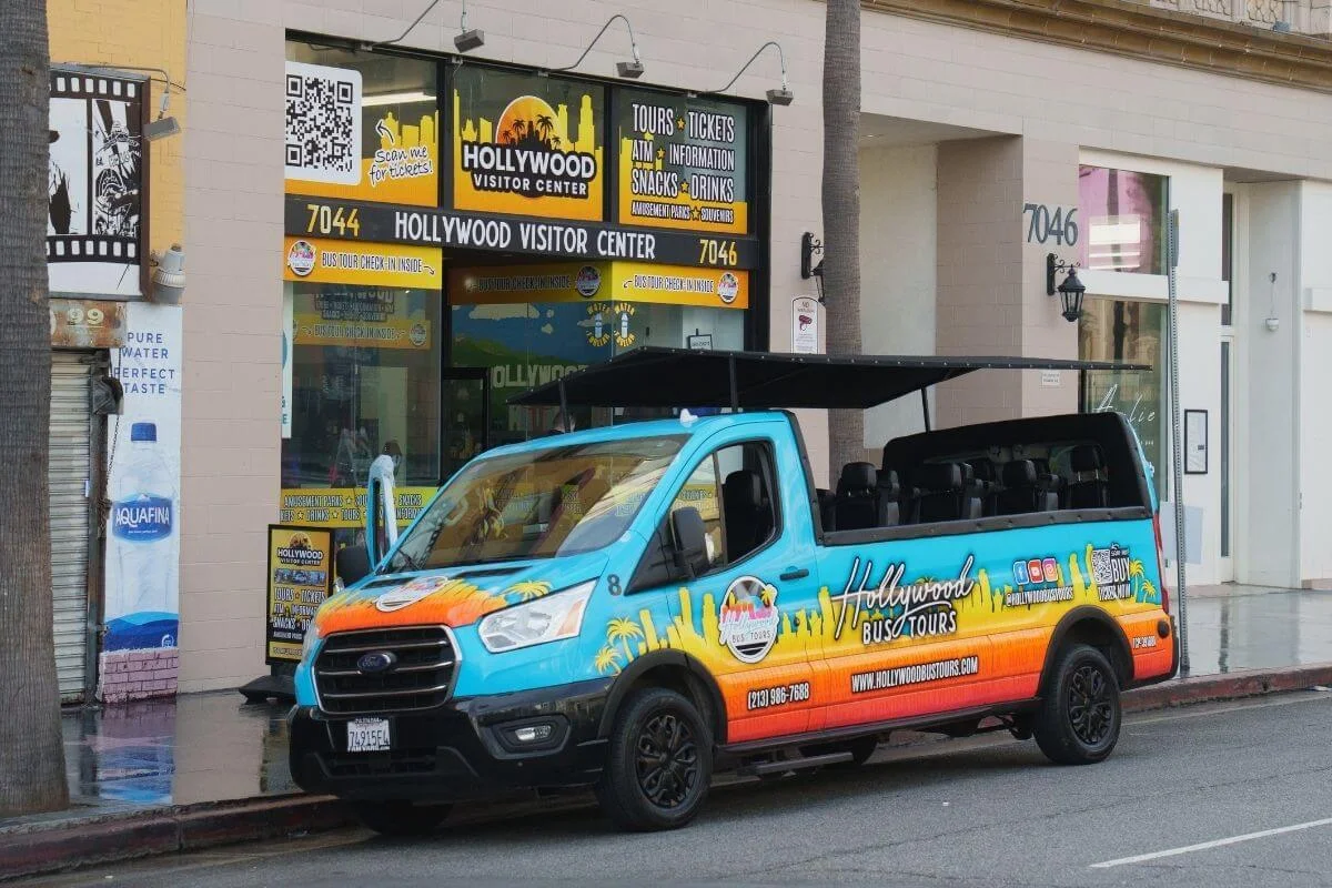 Open top Hollywood Bus Tours vehicle parked outside the Hollywood Visitor Center on Hollywood Boulevard serving as a tour pickup location near the Walk of Fame