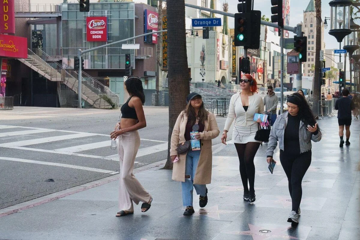 Four women walking on the Hollywood Walk of Fame near Orange Drive and Hollywood Boulevard in Los Angeles.