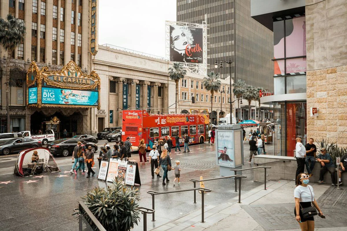 Busy Hollywood Boulevard street scene near El Capitan Theatre with pedestrians, tour bus, and palm lined buildings in Los Angeles