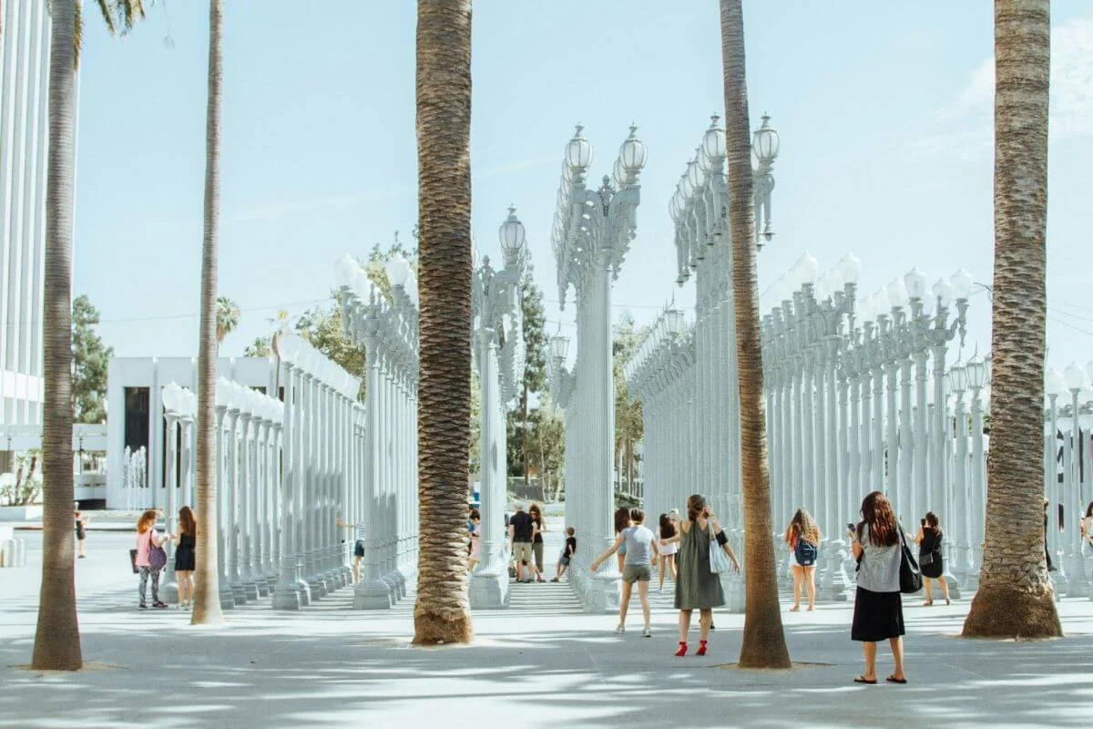 Visitors walking among the Urban Light street lamp installation at the Los Angeles County Museum of Art on a sunny day