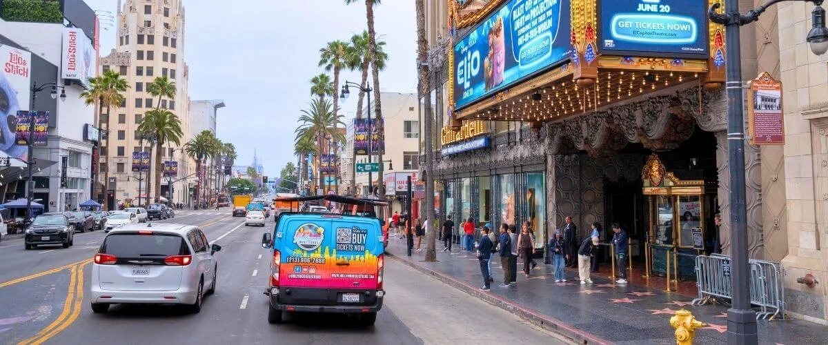 Hollywood bus tour van driving along the Hollywood Walk of Fame near the El Capitan Theatre in Los Angeles