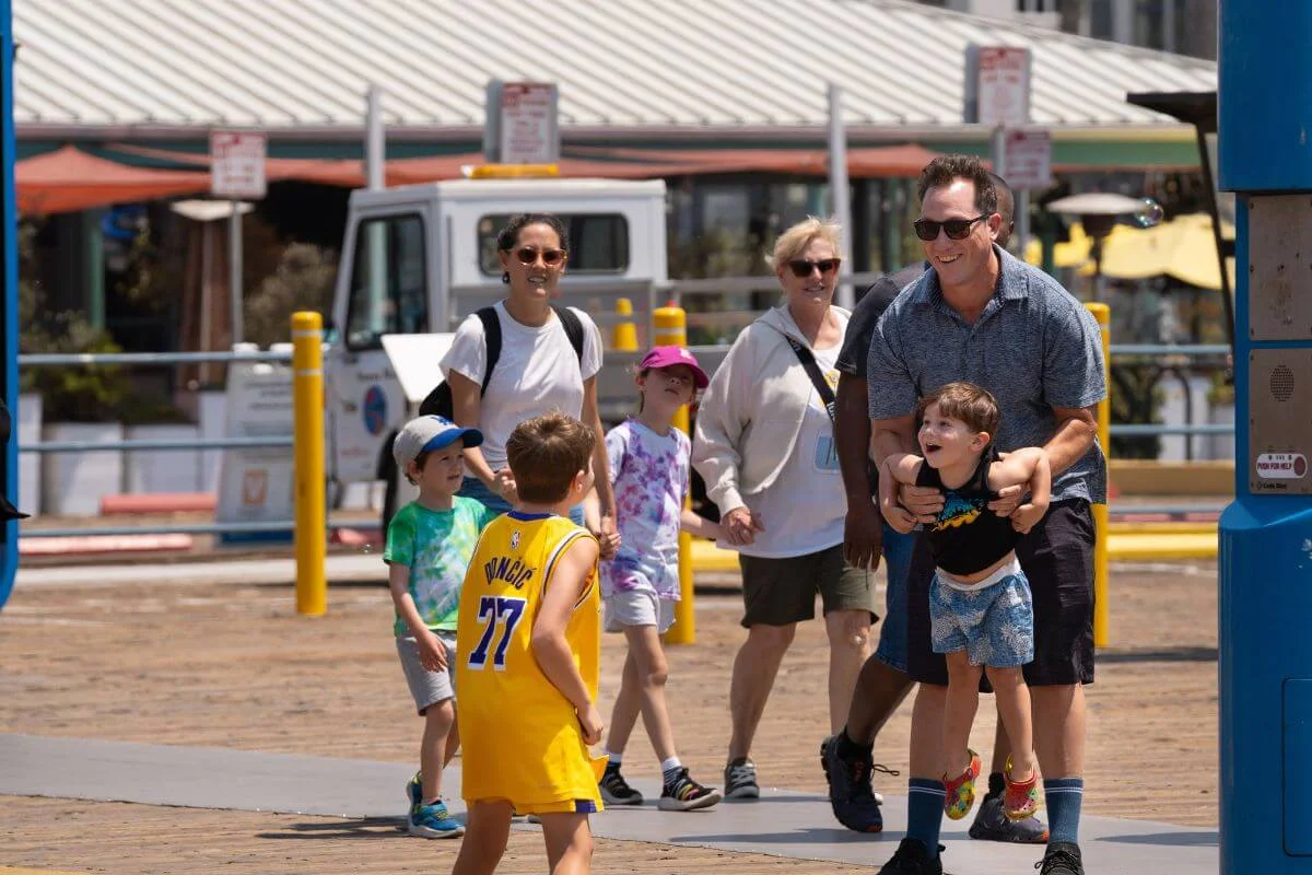 Family with children playing and walking together near Santa Monica Pier in Los Angeles.