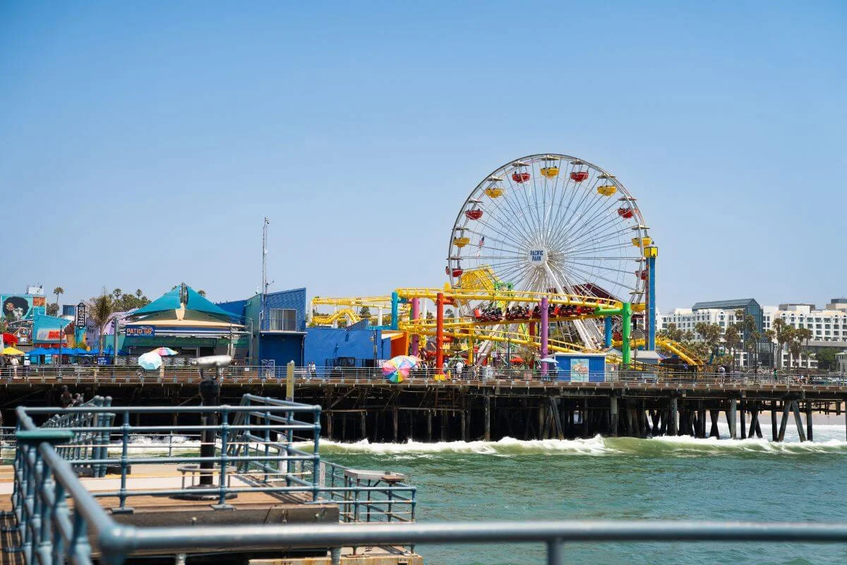 Colorful rides and Ferris wheel at Pacific Park on Santa Monica Pier overlooking the ocean in California.
