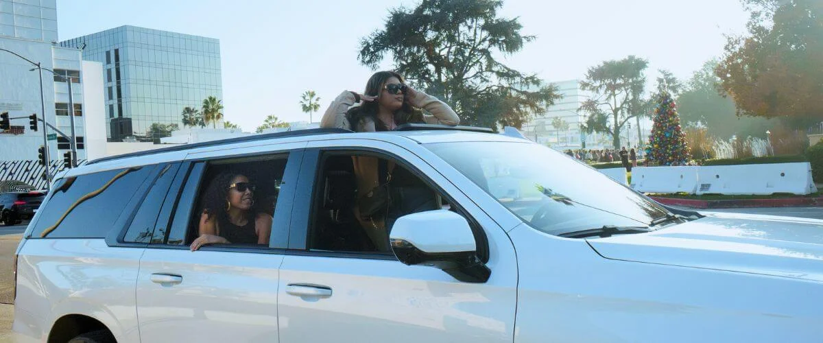 A group of tourists riding in an open vehicle, enjoying a sunny day in Los Angeles while looking out at the city during a sightseeing tour.