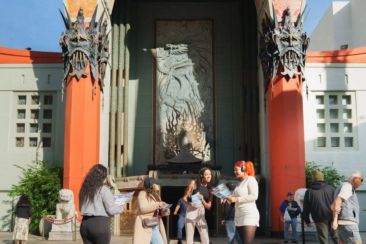 Group of tourists holding maps outside TCL Chinese Theatre in Hollywood, Los Angeles, enjoying a guided sightseeing experience.