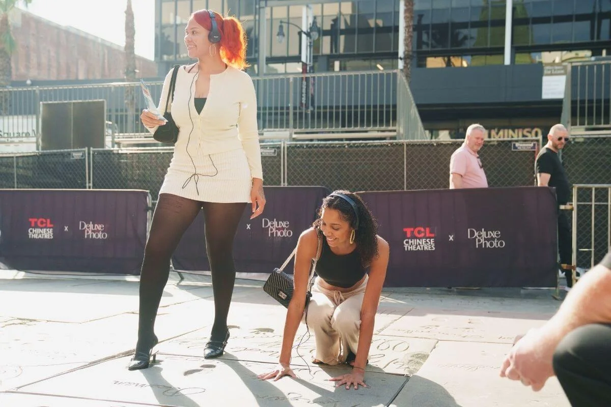 Tourists looking at celebrity handprints and footprints outside TCL Chinese Theatre on the Hollywood Walk of Fame in Los Angeles.