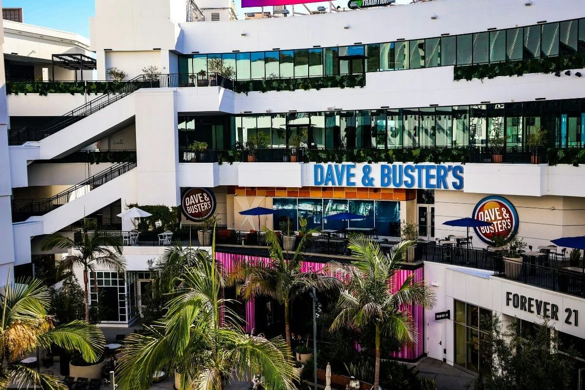 View of Dave & Buster’s and surrounding shops inside Ovation Hollywood shopping complex with palm trees and outdoor terraces in Los Angeles.