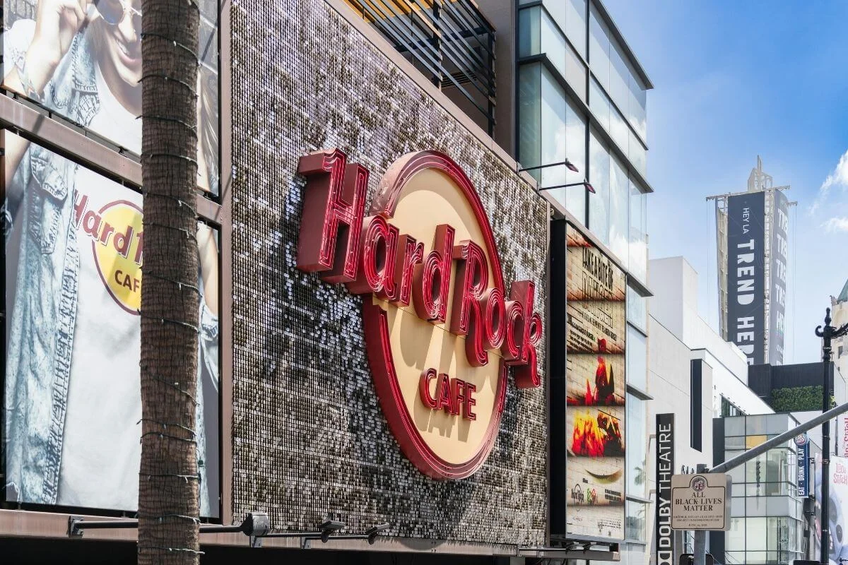 Exterior of Hard Rock Cafe on Hollywood Boulevard with iconic signage and surrounding shops in Los Angeles.