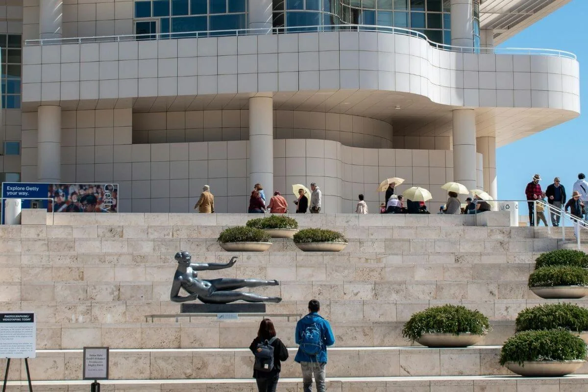 Visitors viewing a modern sculpture on the terrace of the Getty Center, with the museum’s iconic white architecture in Los Angeles.