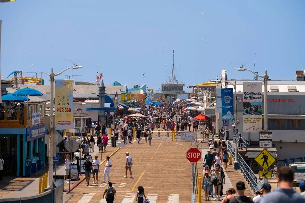 Visitors walking along the busy Santa Monica Pier with shops, attractions, and oceanfront views in Southern California.