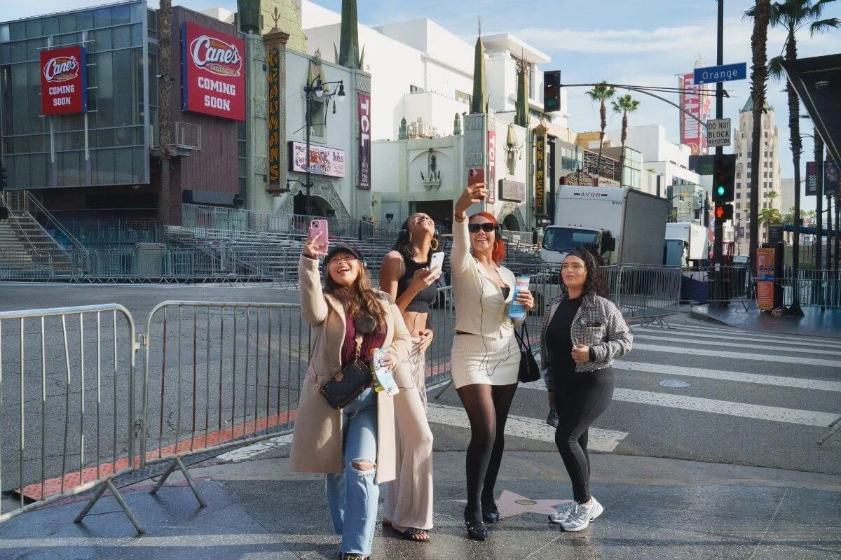 A group of friends taking selfies and posing on Hollywood Boulevard near the TCL Chinese Theatre during a sightseeing trip in Los Angeles.