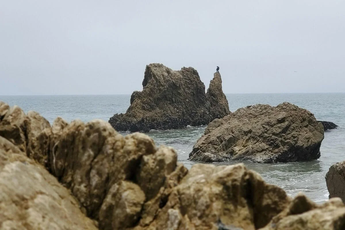 Large jagged rock formations rising from the ocean along the Malibu California coastline