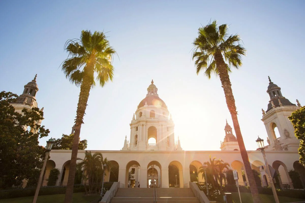 Ornate Pasadena City Hall dome with tall palm trees and sunburst at sunset