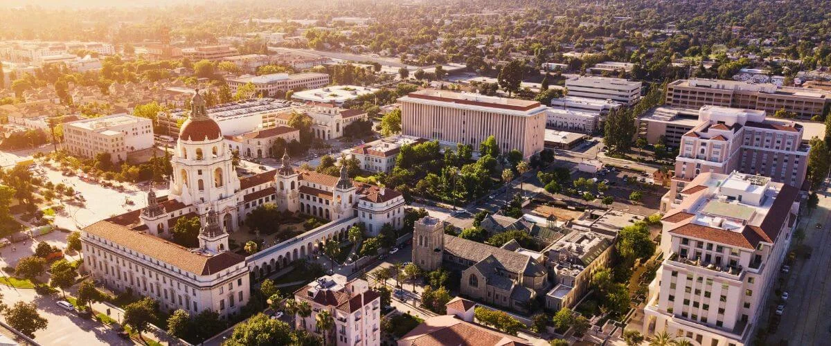 Drone shot of Pasadena City Hall surrounded by tree-lined streets and city buildings at golden hour