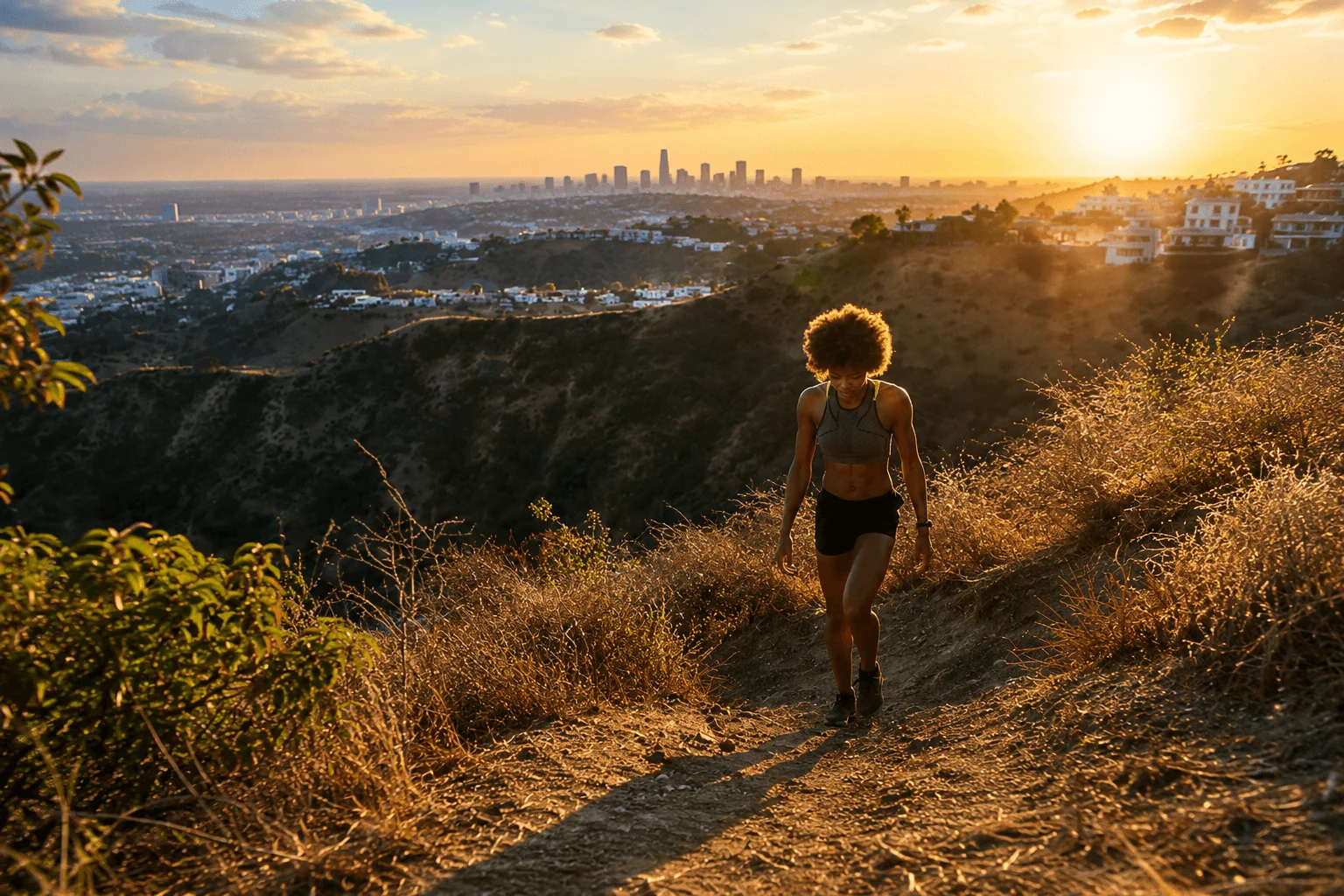 Woman hiking Runyon Canyon trail with LA skyline at sunset