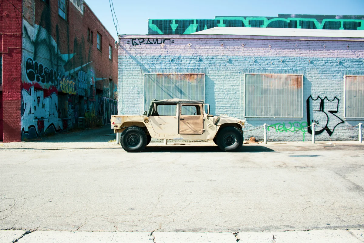 Vintage military Humvee parked in front of graffiti-covered buildings on a Los Angeles street