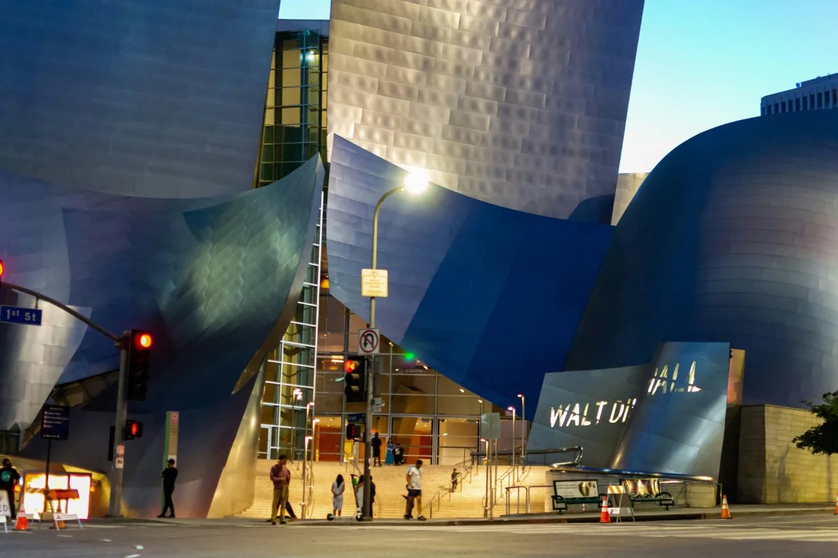 Walt Disney Concert Hall stainless steel exterior lit up at dusk on 1st Street in Los Angeles
