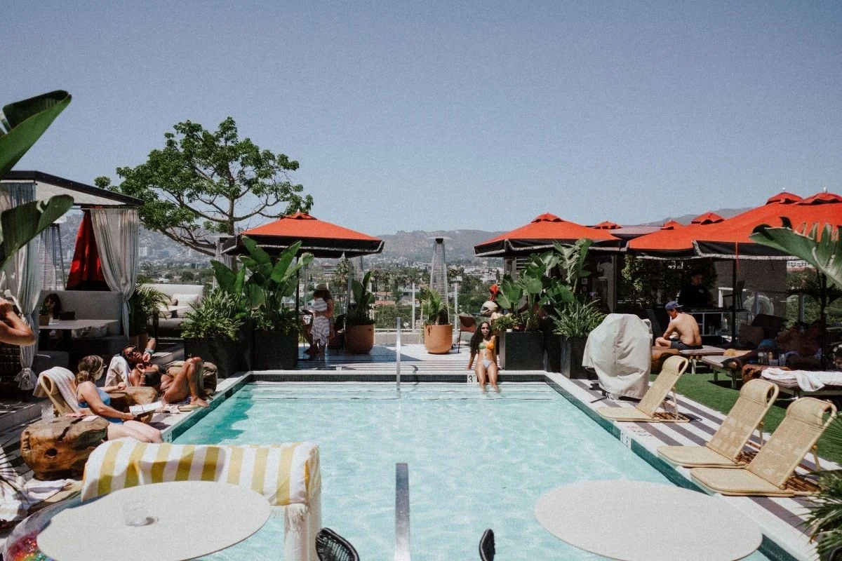 Guests relaxing at rooftop pool with city view in West Hollywood