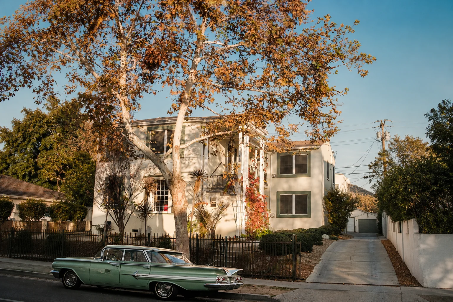 Vintage car parked outside house with autumn foliage in LA