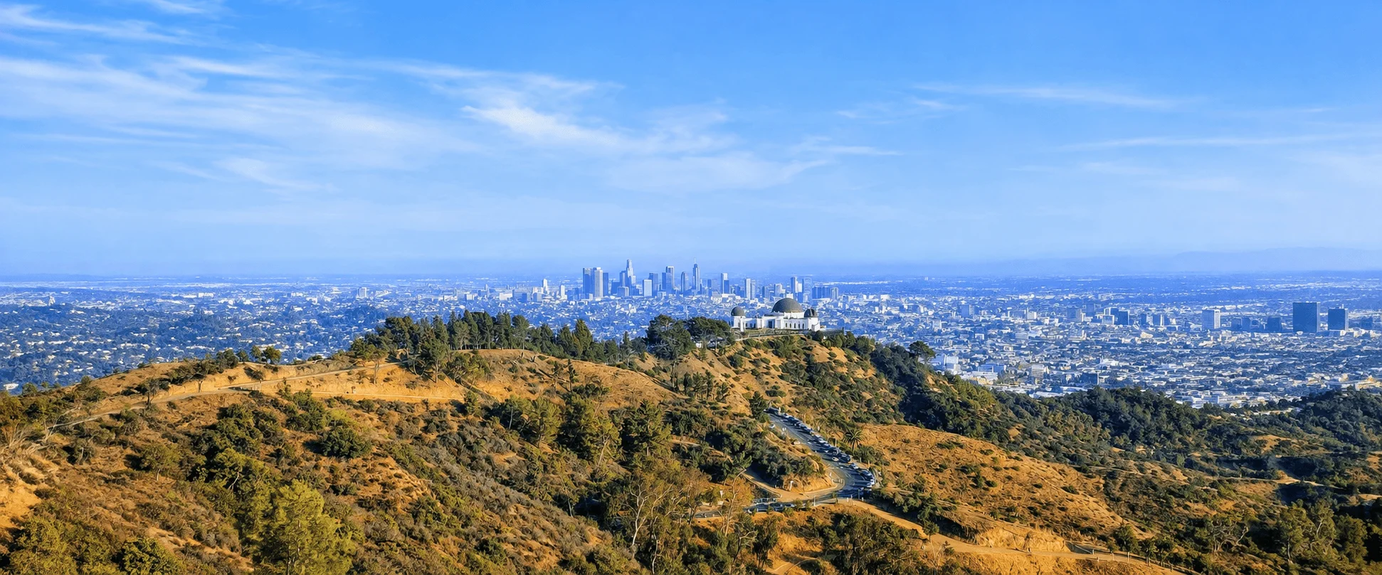 Wide view of Griffith Park hills with Griffith Observatory and the Los Angeles skyline in the distance