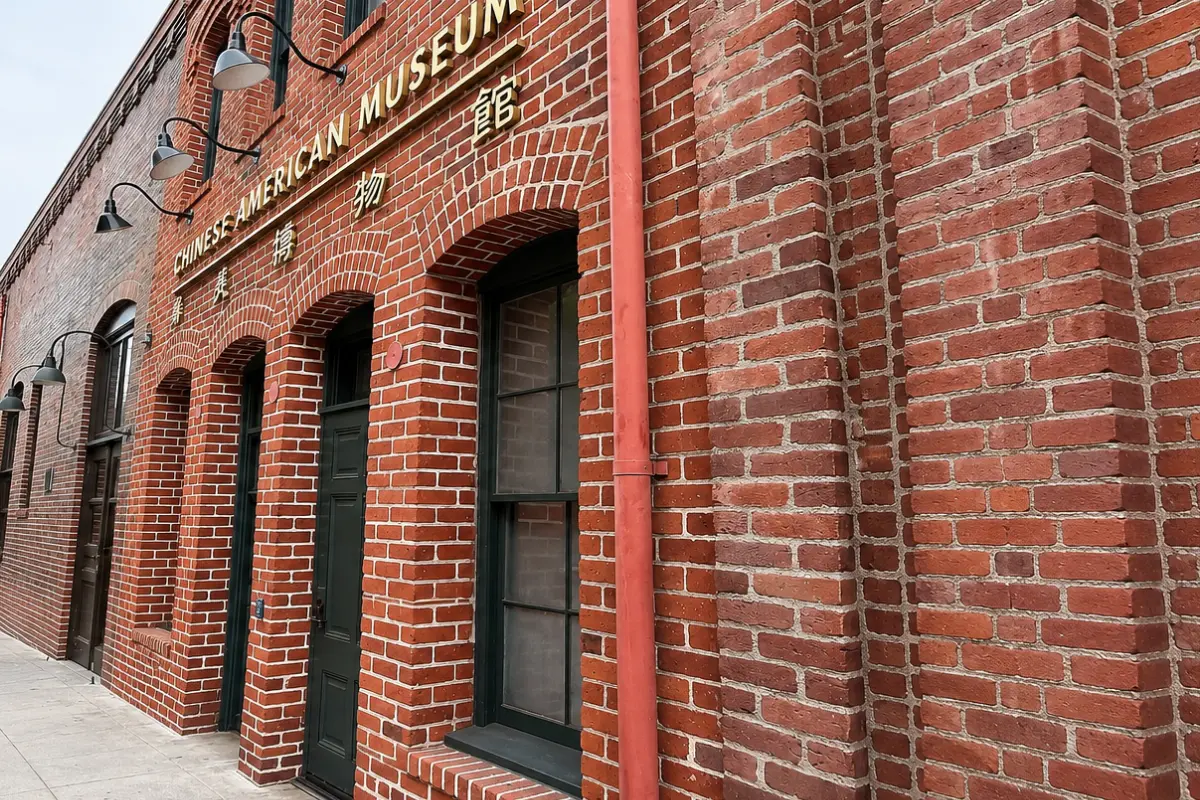 Red brick facade of the Chinese American Museum with gold English and Chinese lettering and arched windows in downtown Los Angeles